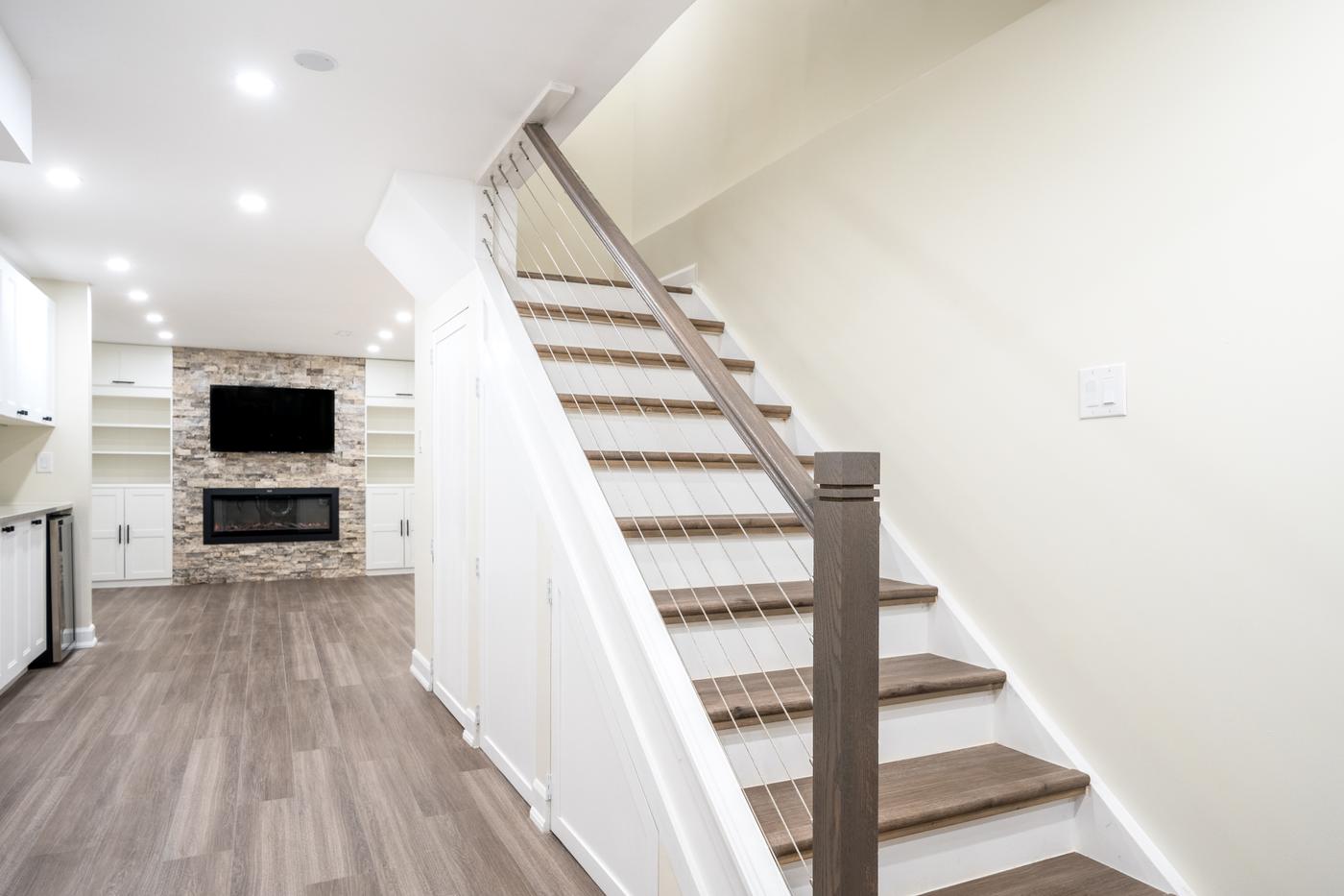 Stone Fireplace Basement Retreat, Oshawa: Staircase leading into the finished basement with the fireplace wall beyond