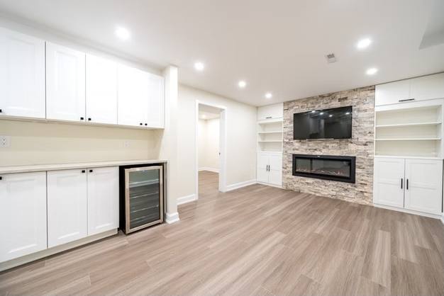 Stone Fireplace Basement Retreat, Oshawa: Built-in cabinets and a stone fireplace wall with a wine fridge