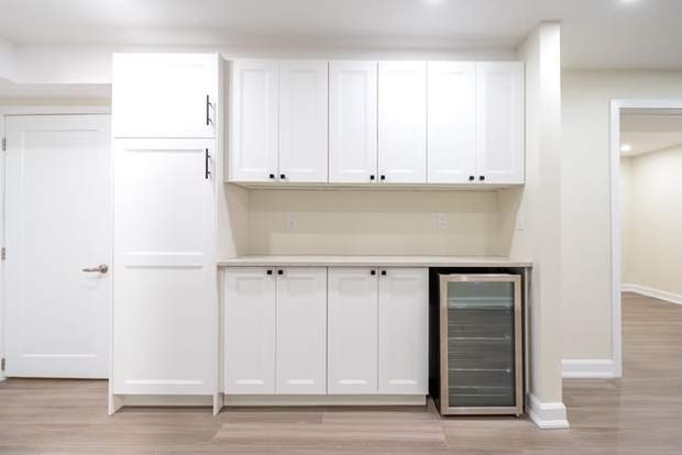Stone Fireplace Basement Retreat, Oshawa: Cabinet wall with wine fridge and pantry
