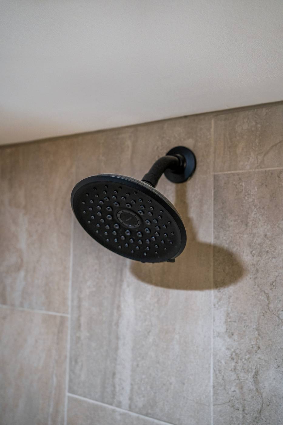 Taupe Herringbone Bathroom Retreat, Whitby: Black rain shower head on large-format tile