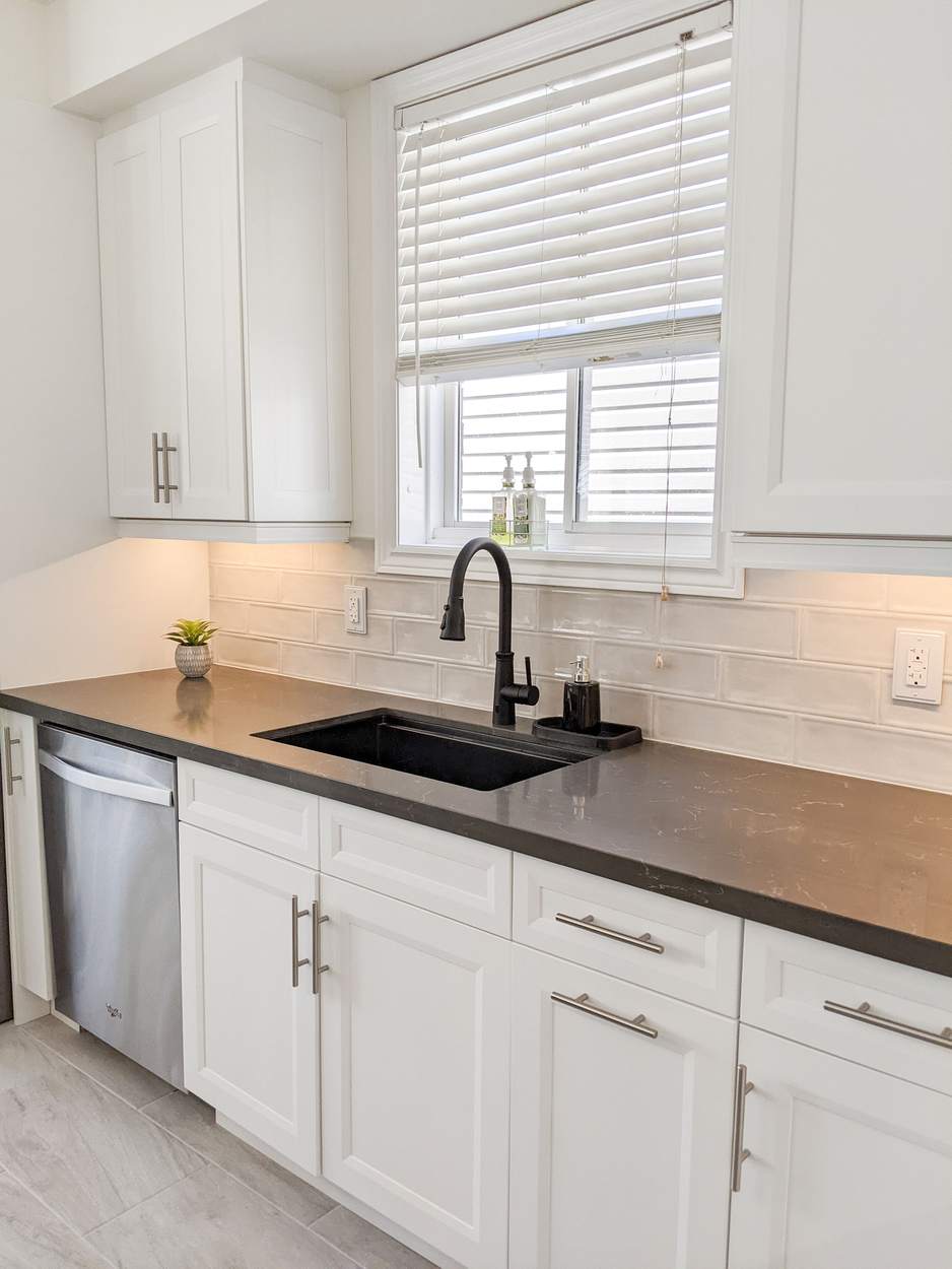 Chef's Kitchen and Entertainer's Basement, Whitby: Undermount sink under a window with a dark quartz counter and subway backsplash