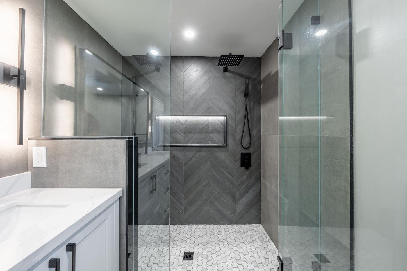 Slate Chevron Spa Bathroom, Ajax: Glass shower with a hexagon tile floor and lit niche