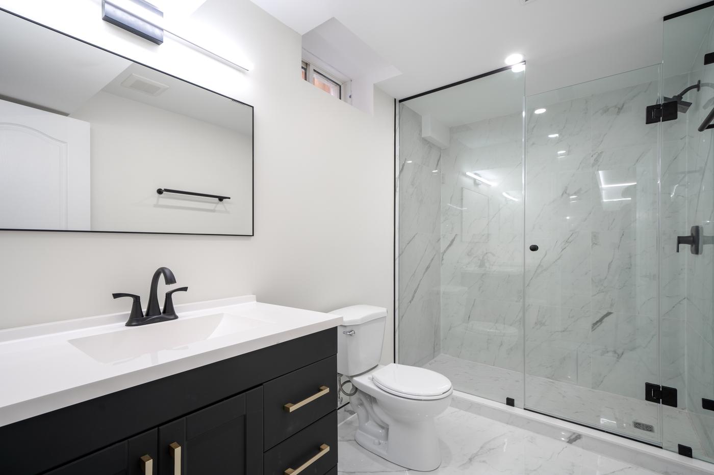 Open-Concept Basement Suite, Oshawa: Bathroom with a dark vanity, brass pulls and glass shower