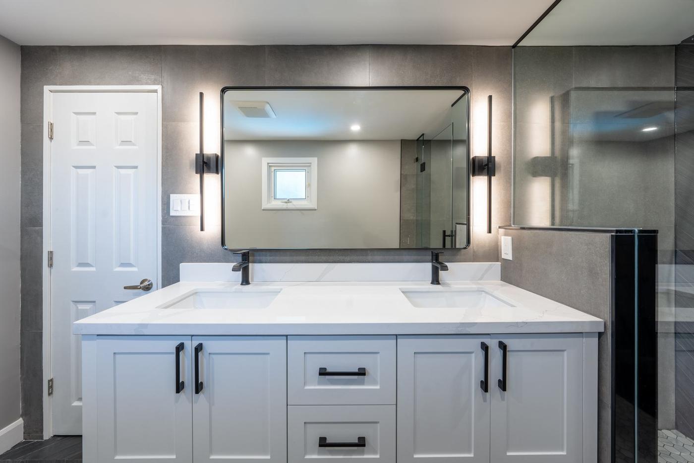 Slate Chevron Spa Bathroom, Ajax: Double vanity with two black sconces and a framed mirror
