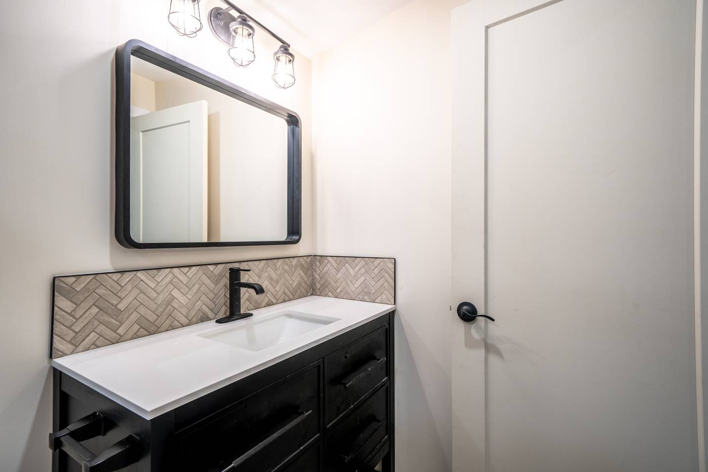Taupe Herringbone Bathroom Retreat, Whitby: Black vanity with a quartz top and herringbone backsplash