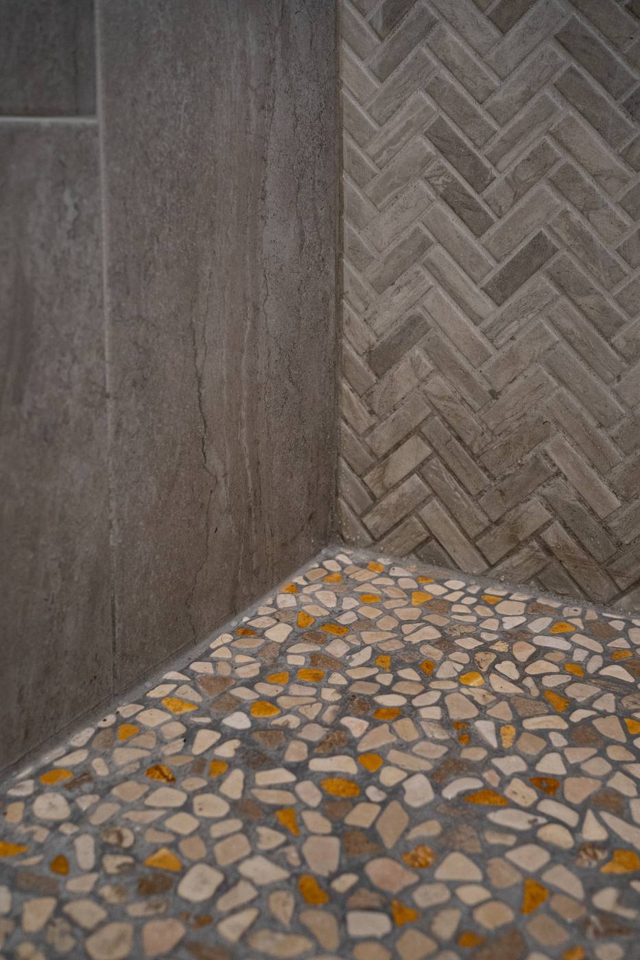 Taupe Herringbone Bathroom Retreat, Whitby: Shower corner where large-format tile meets herringbone and a pebble floor