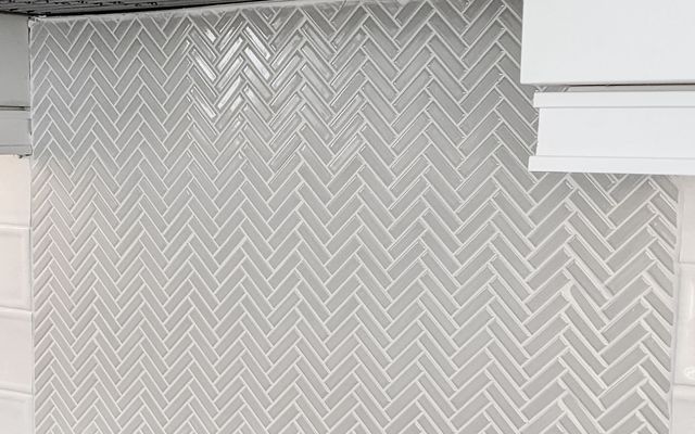 Grey glass herringbone mosaic behind a range