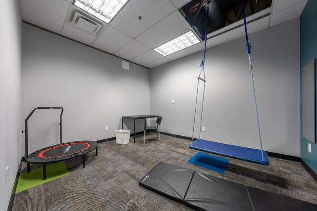 Dots for Kids Occupational Therapy Centre, Whitby: Therapy room with a mini trampoline, balance bar and hanging swing bench