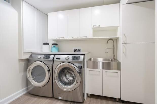 Stone Fireplace Basement Retreat, Oshawa: Laundry room with sink and upper cabinets
