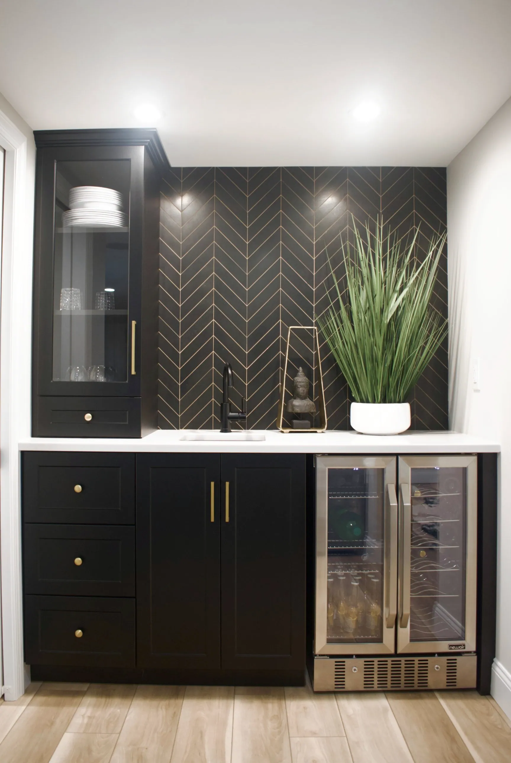 Basement wet bar with black shaker cabinets, a chevron tile backsplash and a beverage fridge