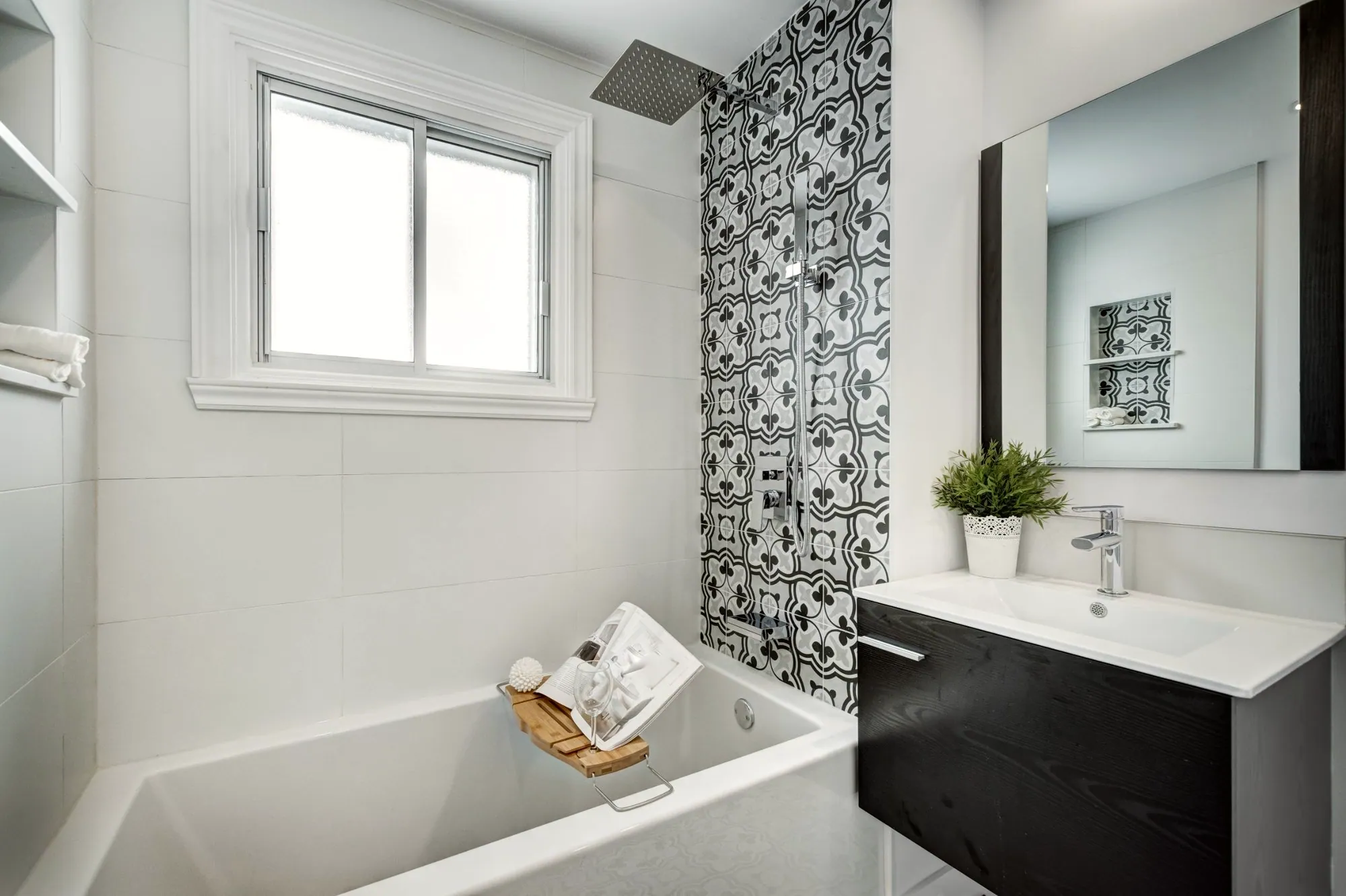 Bathroom with a black-and-grey patterned tile shower wall, rain shower over a soaker tub and a floating dark wood vanity