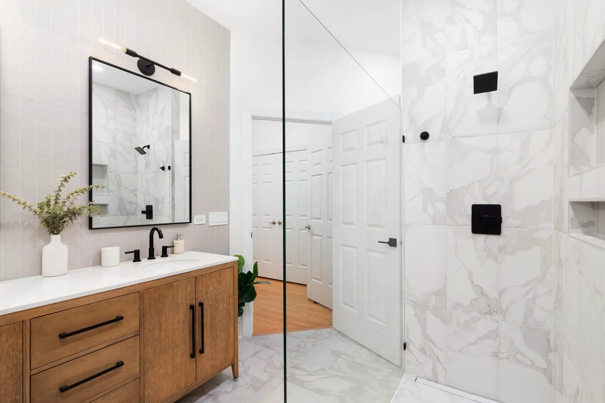 Bathroom with vertical pink tile, a wood vanity, black fixtures and a marble-look walk-in shower