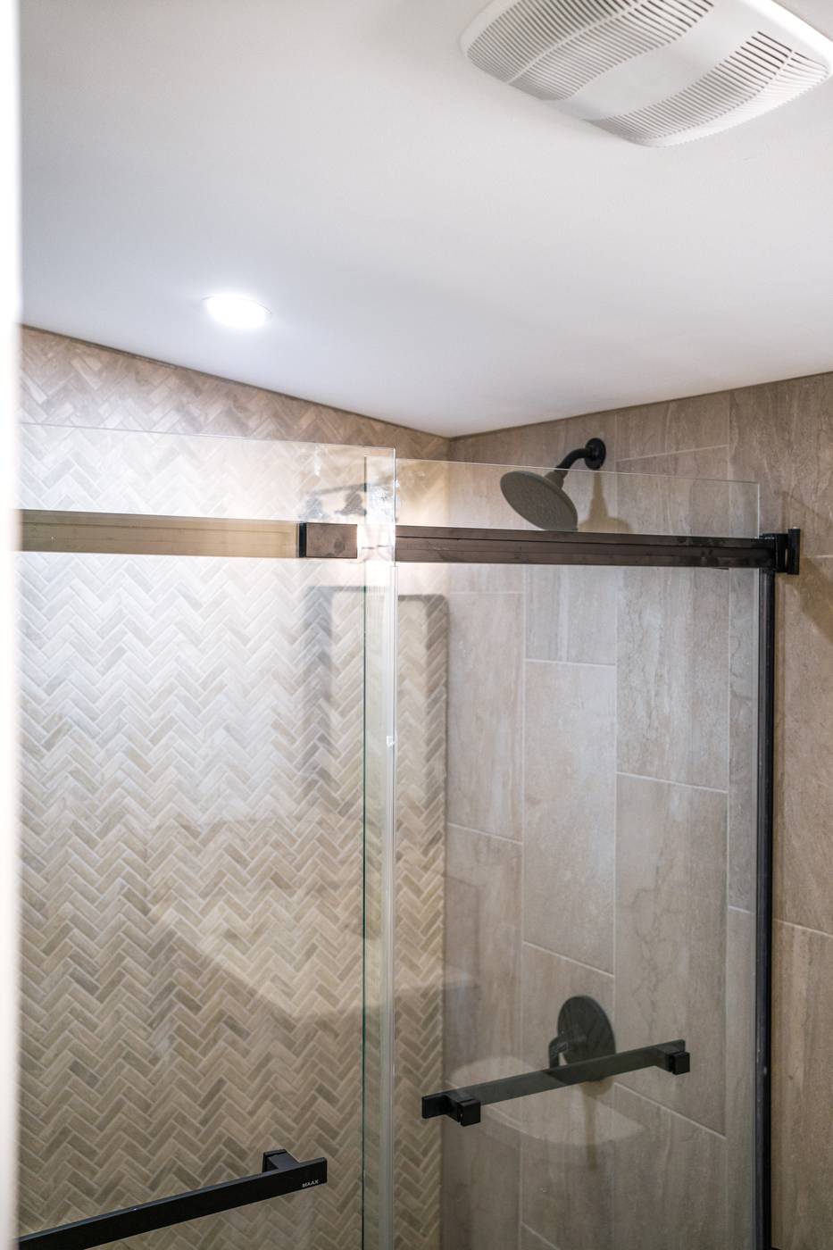 Taupe Herringbone Bathroom Retreat, Whitby: Sliding shower door with a black rain head and hardware