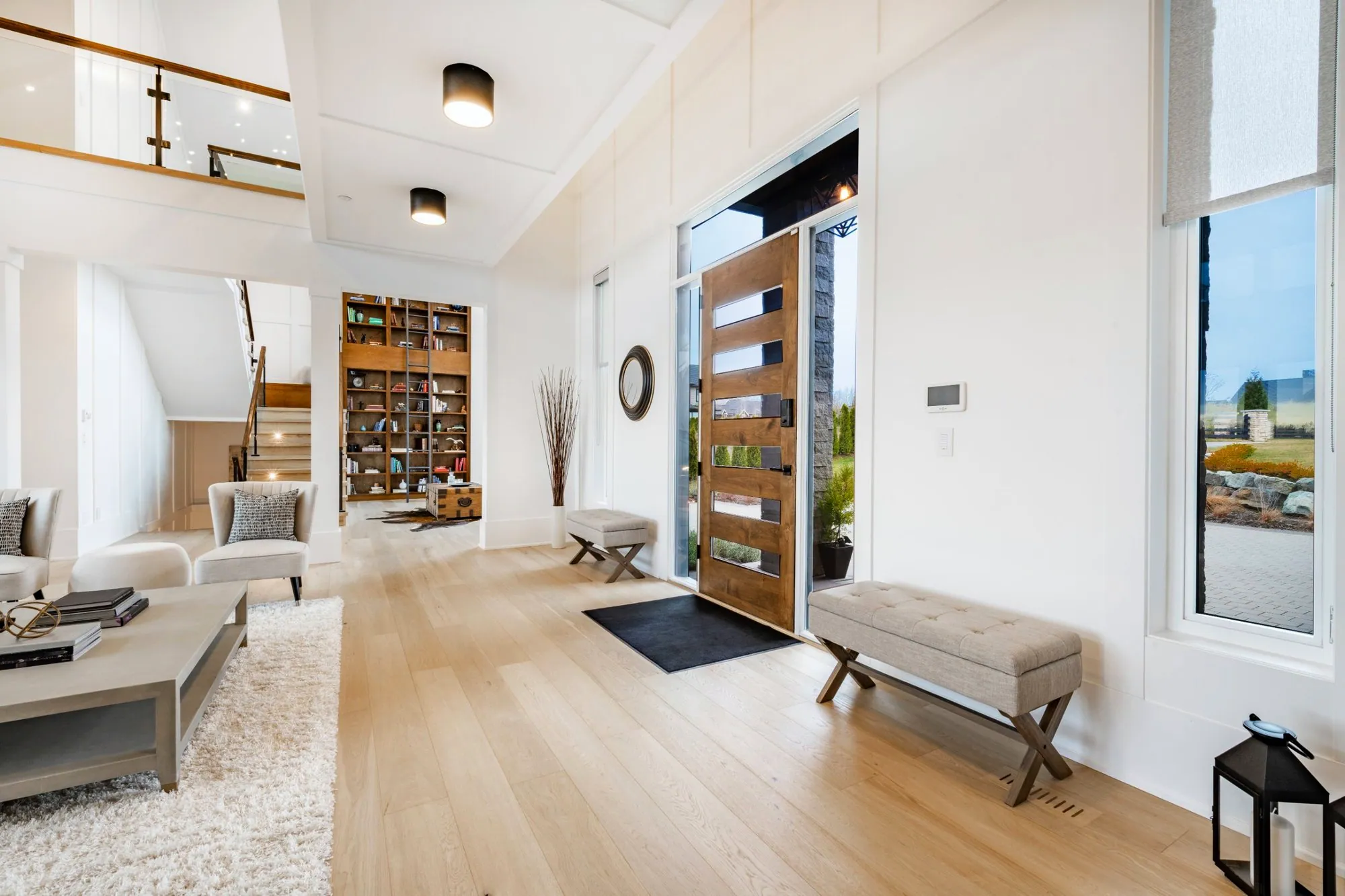 Bright foyer with wide-plank oak floors, a wood pivot front door and panelled walls