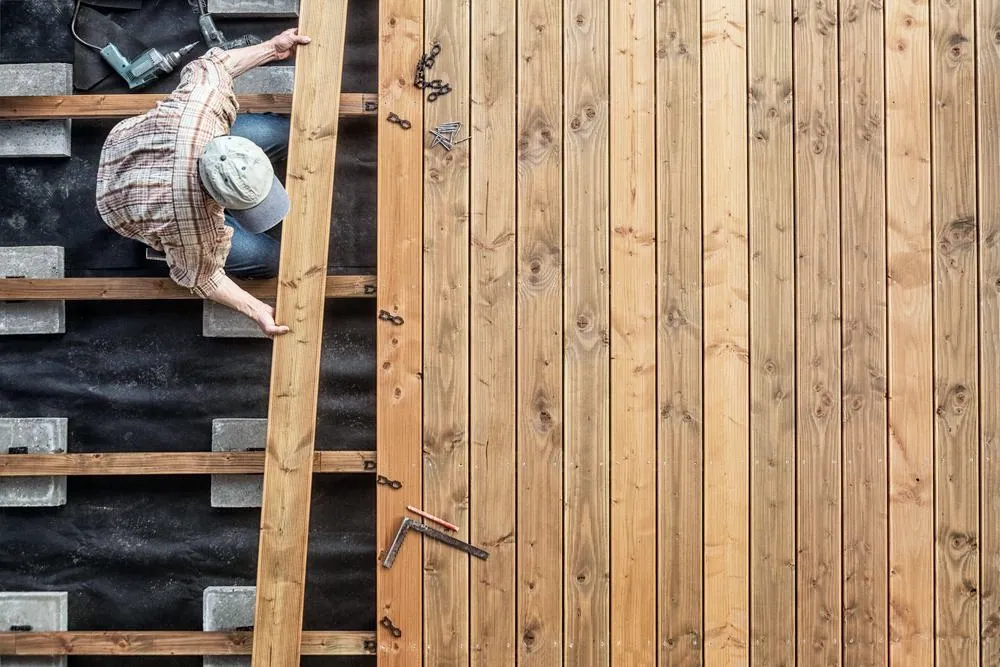 Carpenter laying deck boards over a joist frame