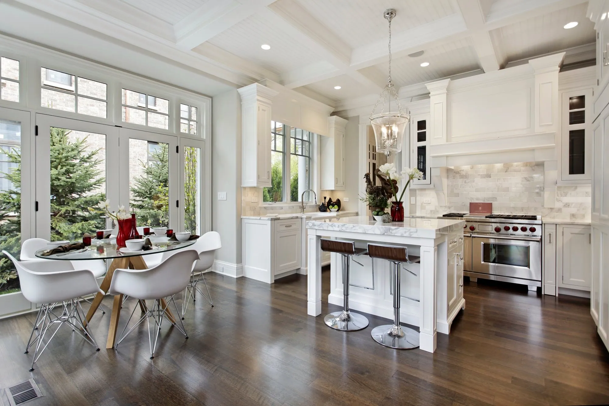 Classic white kitchen with a coffered ceiling, marble island, professional range and a sunny eating area