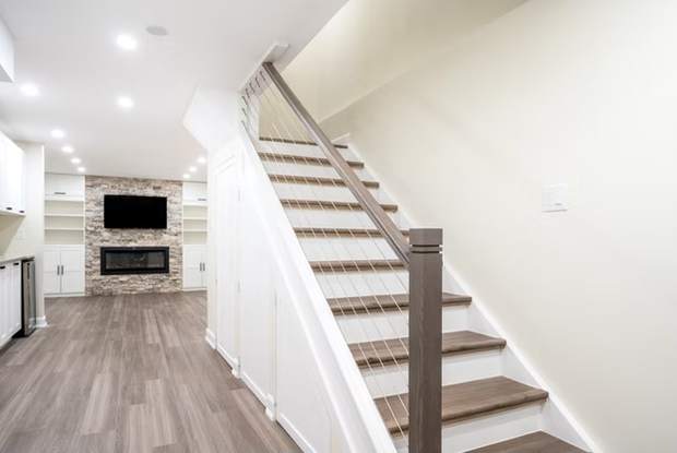 Stone Fireplace Basement Retreat, Oshawa: Staircase with cable railing leading into the finished basement