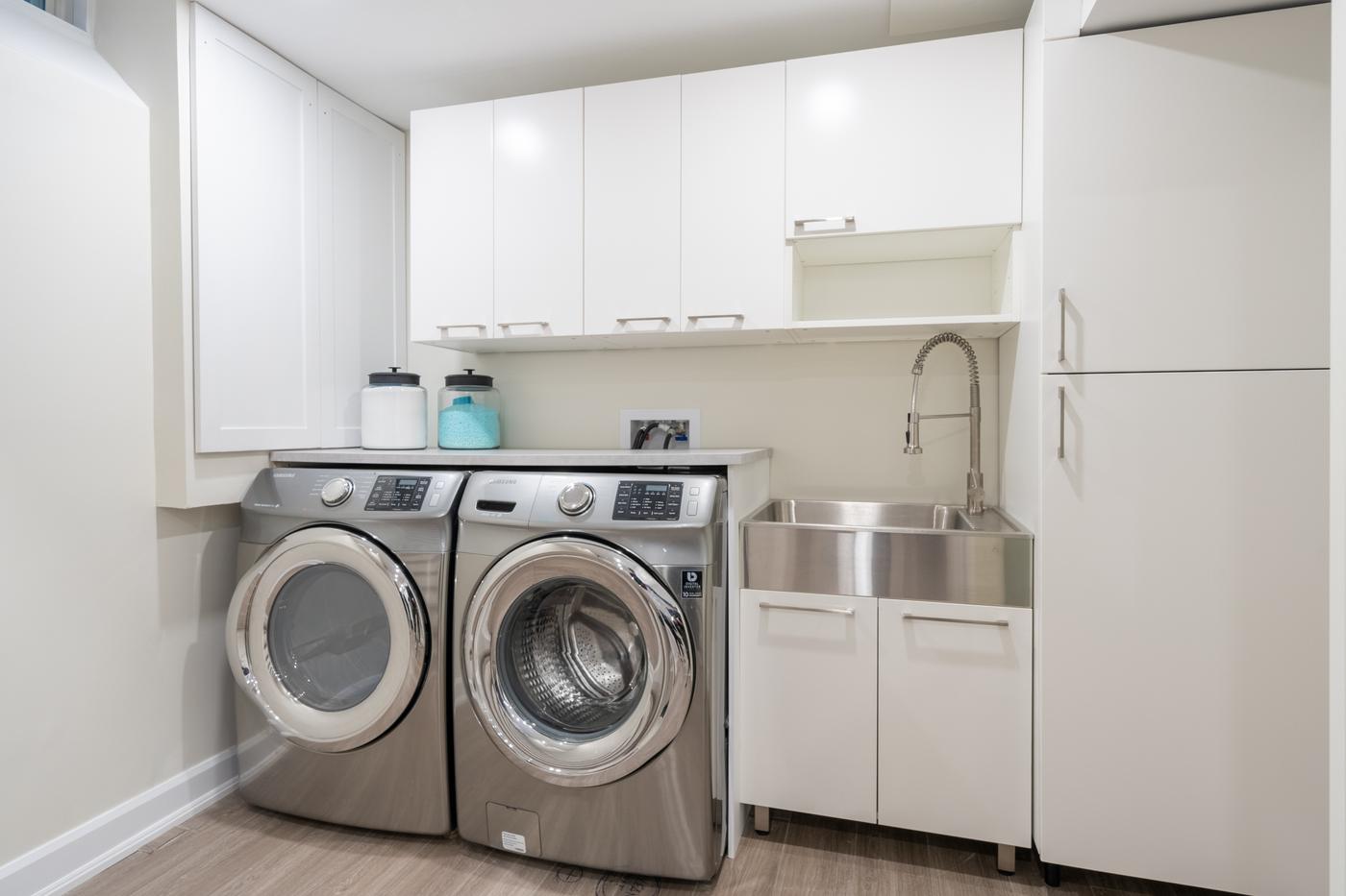 Stone Fireplace Basement Retreat, Oshawa: Laundry room with a utility sink, washer, dryer and upper cabinets