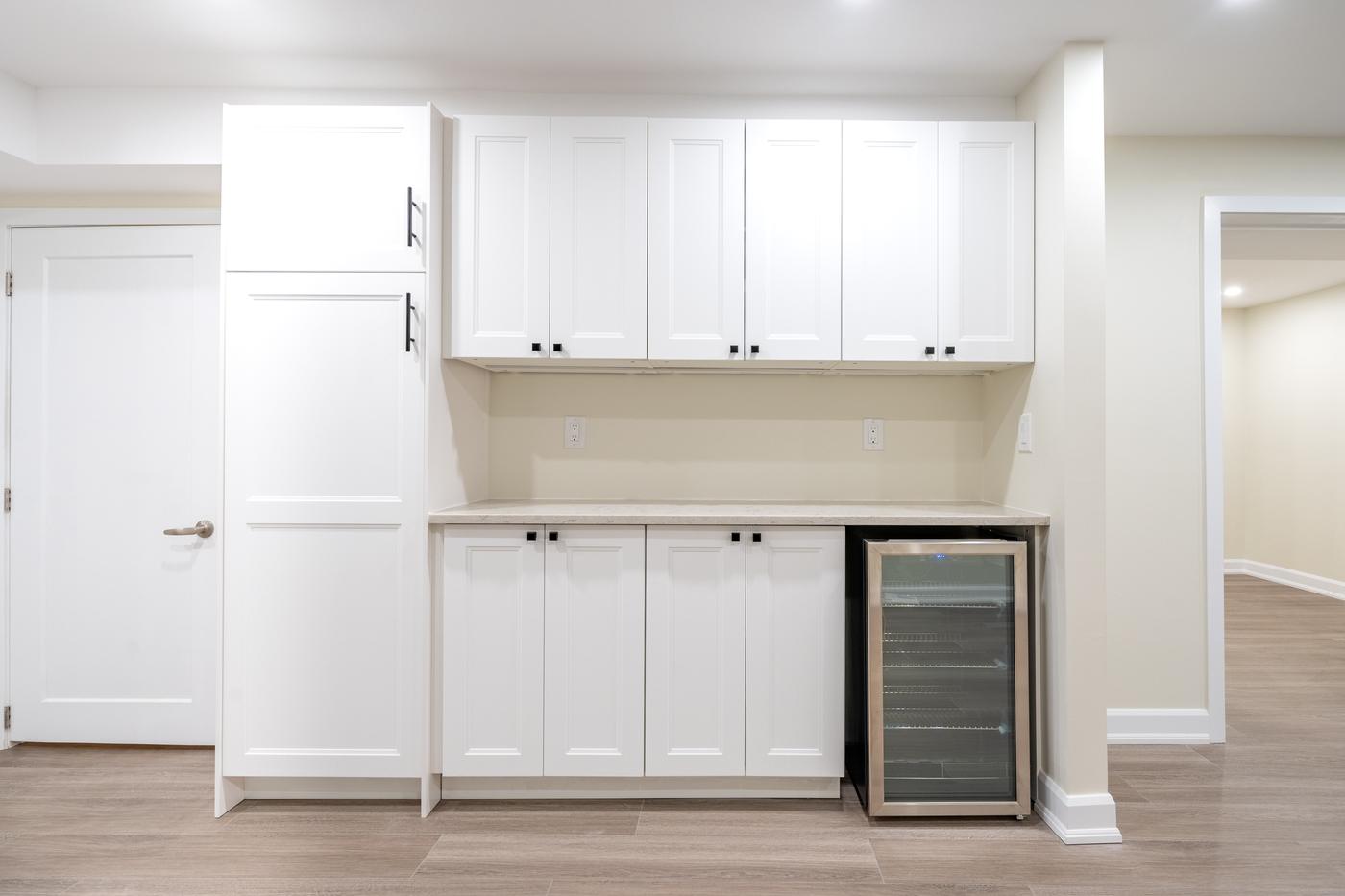 Stone Fireplace Basement Retreat, Oshawa: Cabinet wall with a wine fridge and pantry