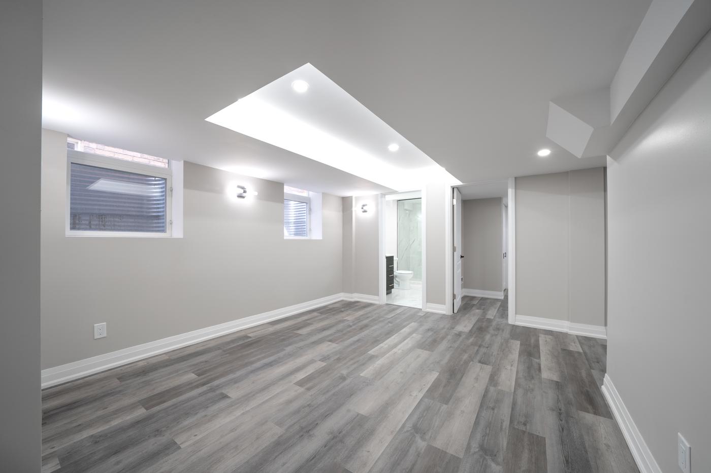 Open-Concept Basement Suite, Oshawa: Living area with a tray ceiling, cove lighting and window wells