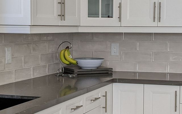 Grey glossy subway tile backsplash above a dark counter