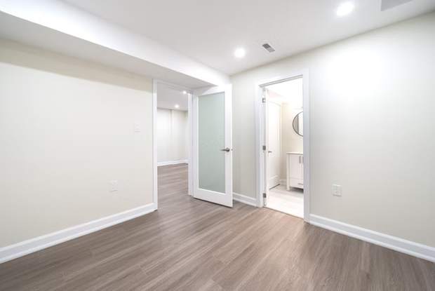 Stone Fireplace Basement Retreat, Oshawa: Open basement with a hallway to the bathroom