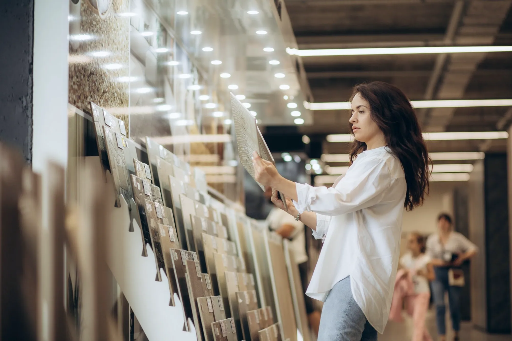 Homeowner comparing large porcelain tile samples in a tile showroom