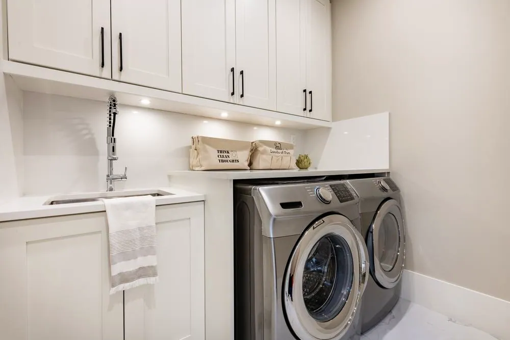 Laundry room with white shaker cabinets, a quartz counter, sink and front-load washer and dryer