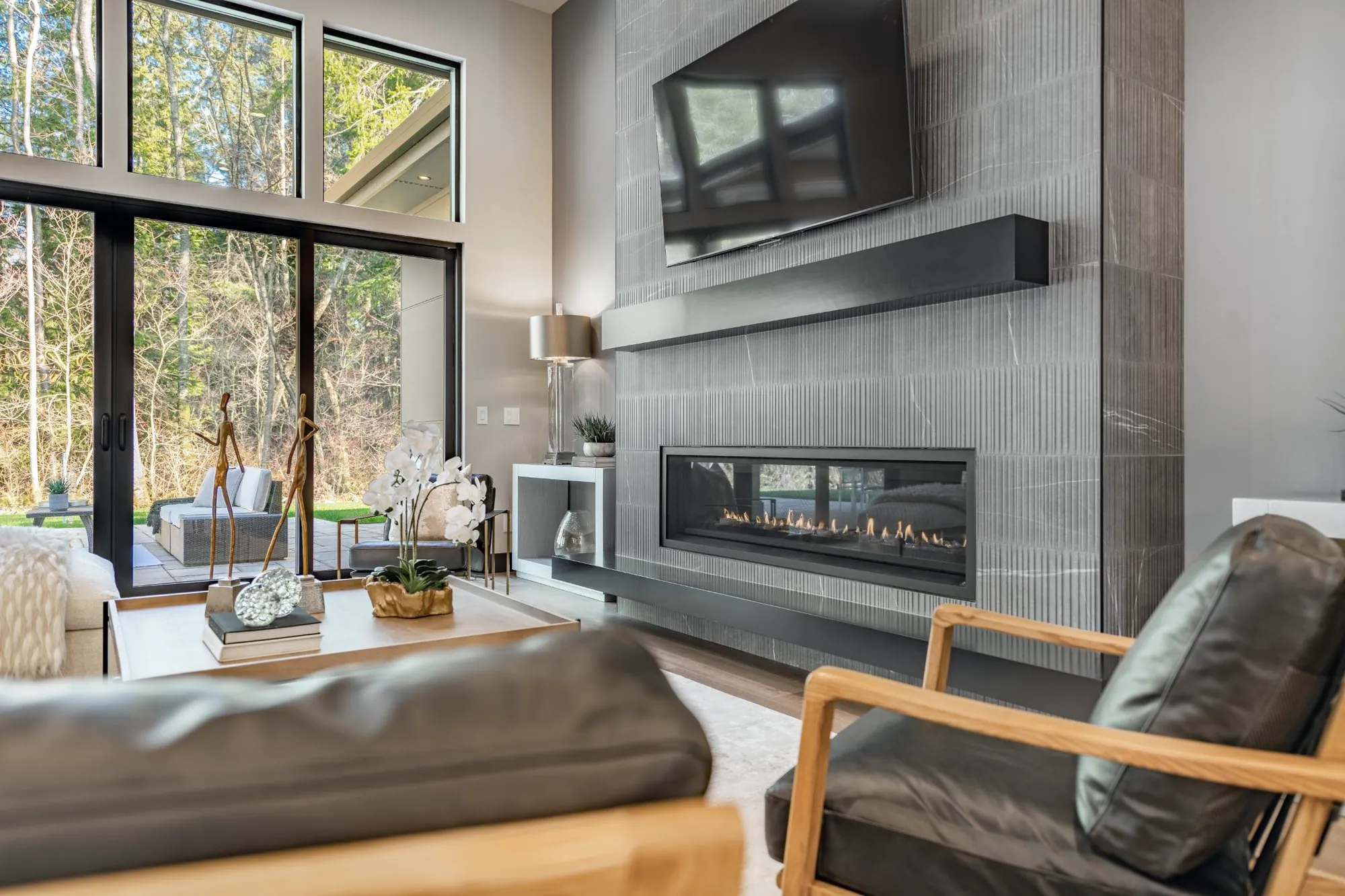 Living room with a floor-to-ceiling grey tile fireplace wall, linear gas fireplace and floating black mantel