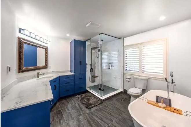 Marble and Navy Primary Ensuite: Blue vanity, glass shower and freestanding tub
