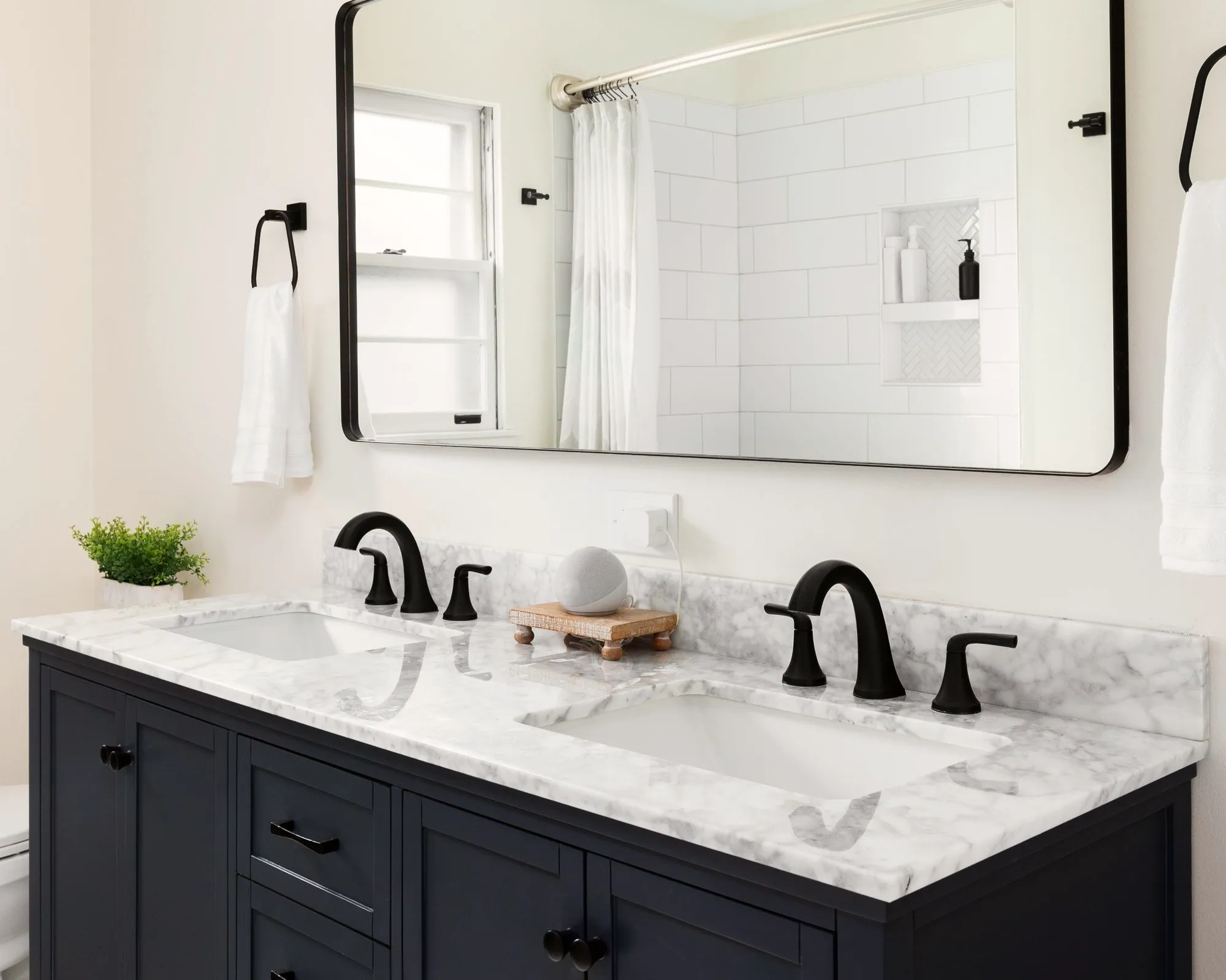 Navy double vanity with a marble top, black faucets and a black-framed mirror
