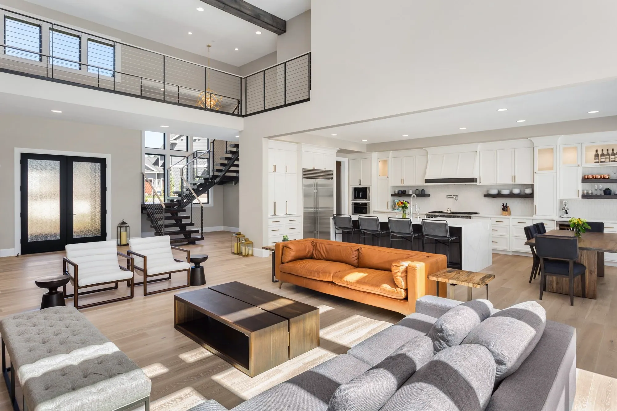Open-concept living room and kitchen with a cable-rail loft, light oak floors and a leather sofa