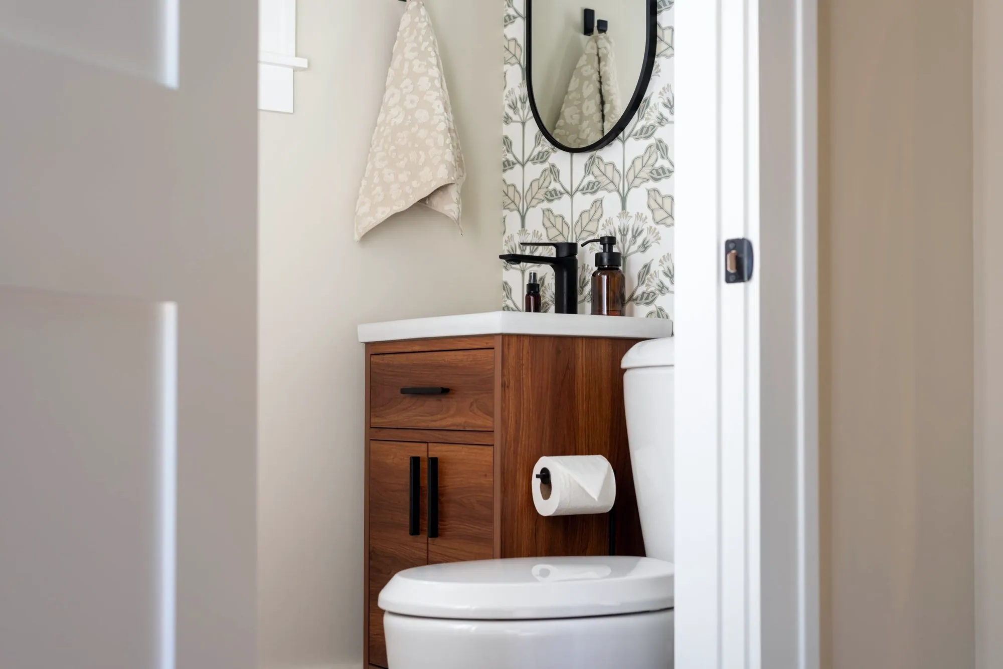Powder room with botanical wallpaper, a walnut vanity and black fixtures