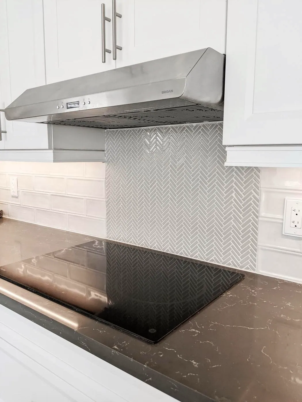 Chef’s Kitchen & Entertainer’s Basement, Whitby: Stainless range hood over a herringbone mosaic backsplash