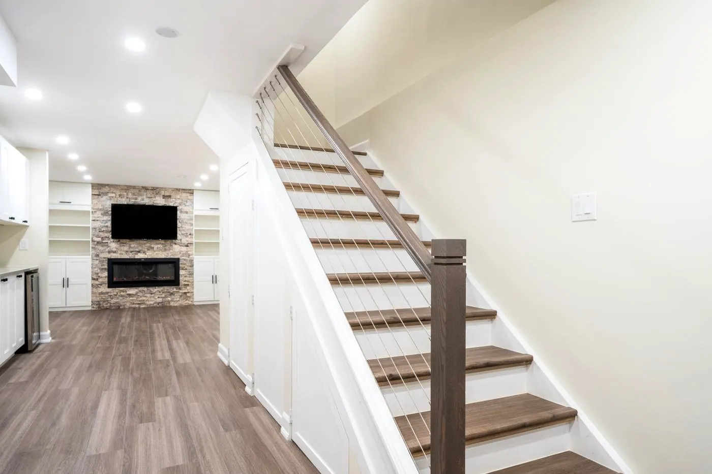 Stone Fireplace Basement Retreat, Oshawa: Staircase leading into the finished basement with the fireplace wall beyond