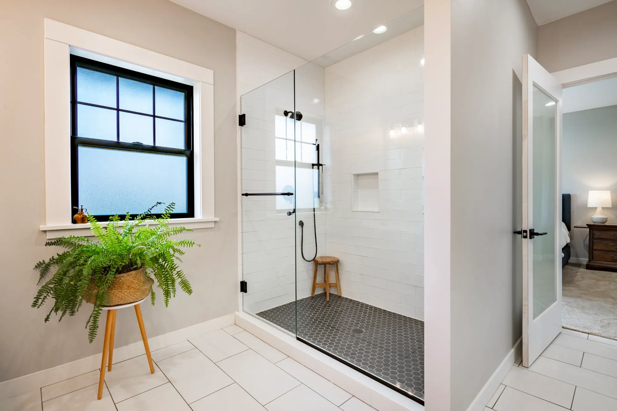 Walk-in shower with white subway tile, a charcoal hexagon floor and black fixtures